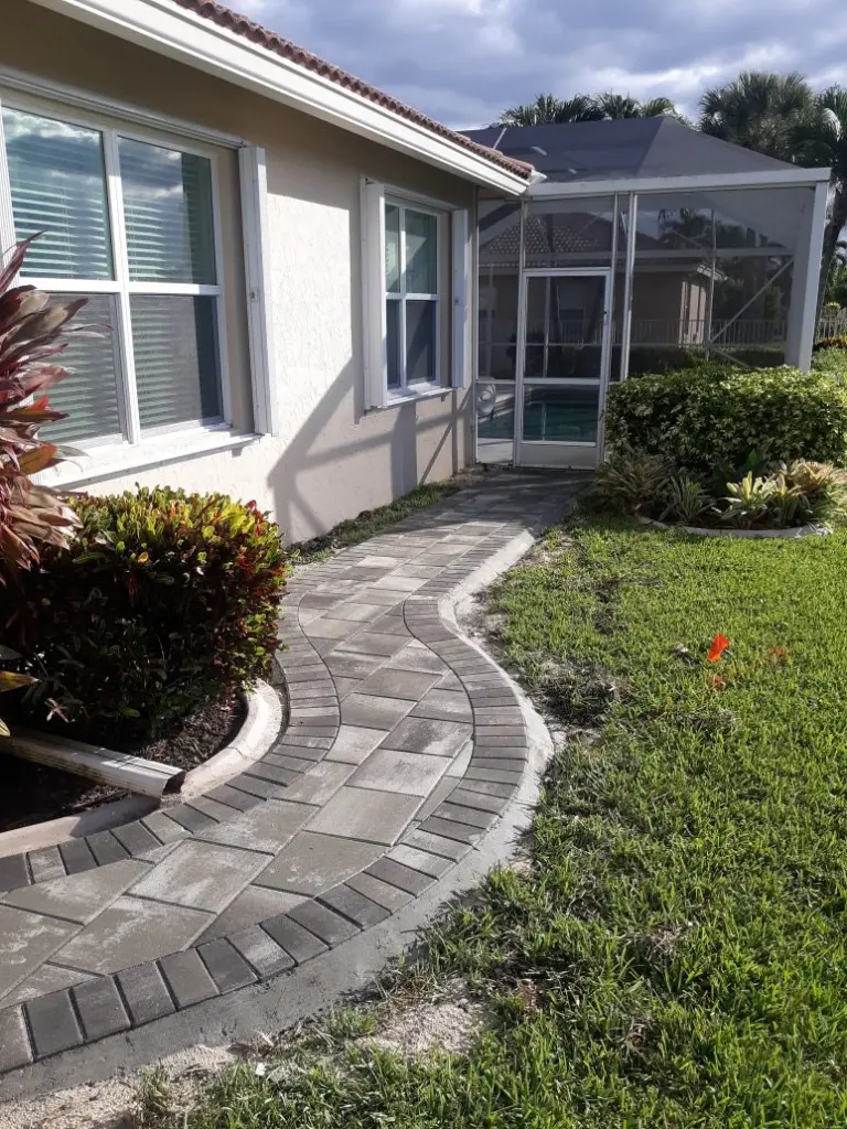 Curving grey paver walkway running along the side of a house