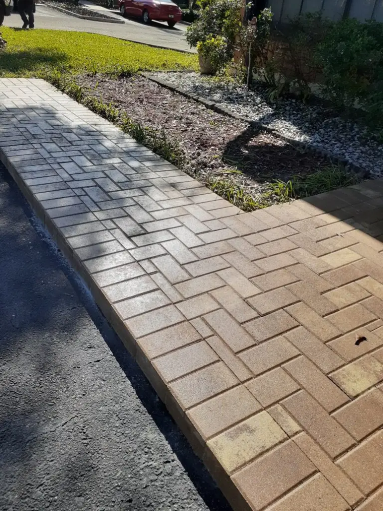 Herringbone paver strip between a driveway and planting bed