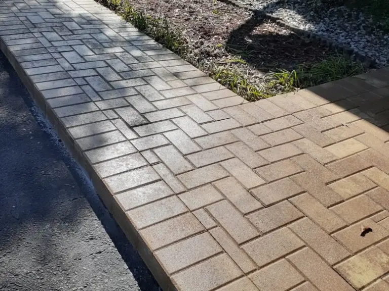Herringbone paver strip between a driveway and planting bed